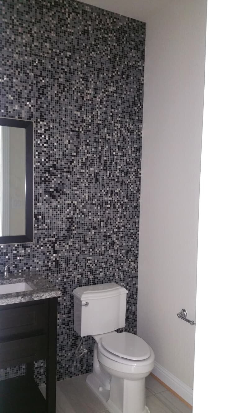 Finished restroom with toilet, vanity and mosaic accent wall