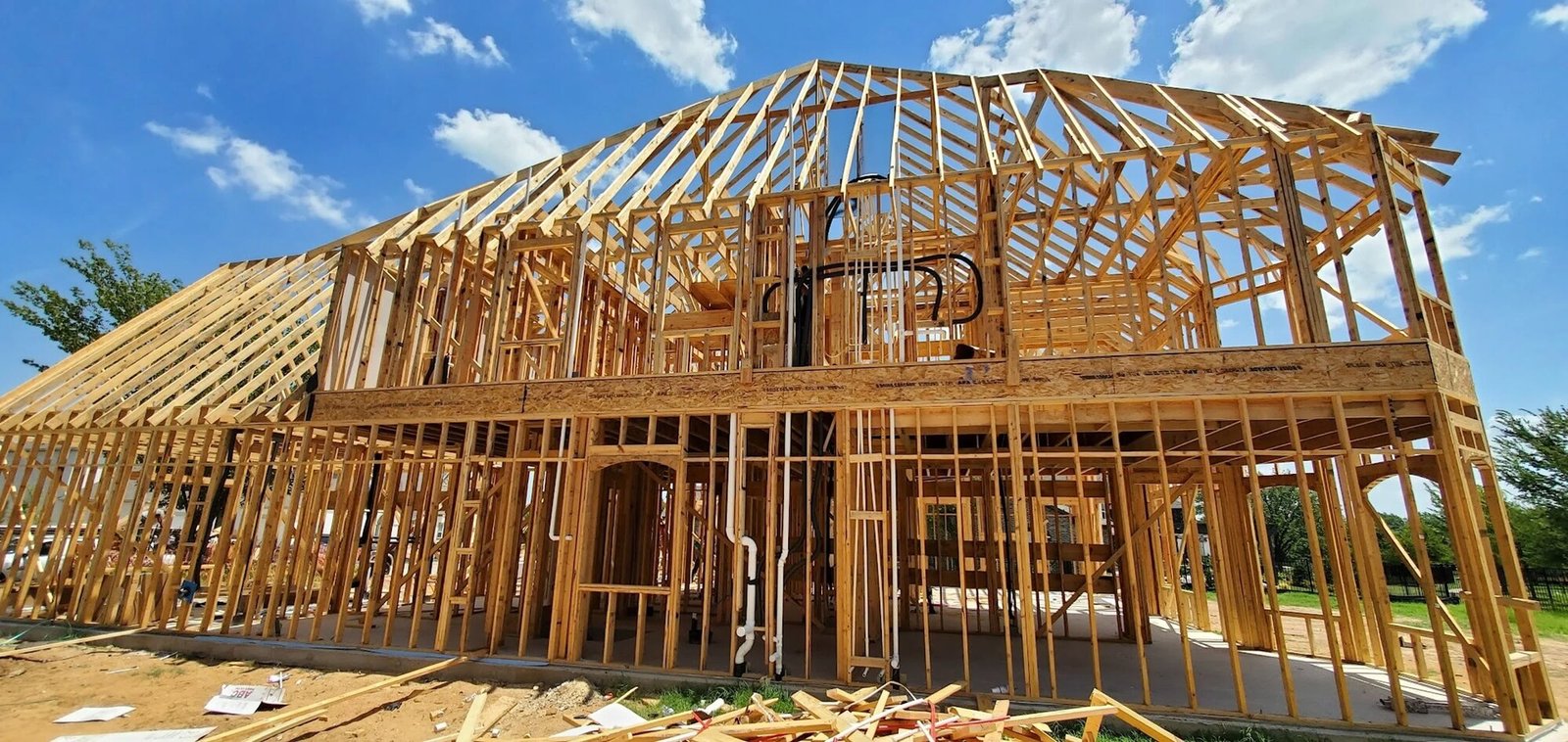 Framed house under construction with roof trusses and plumbing rough-in