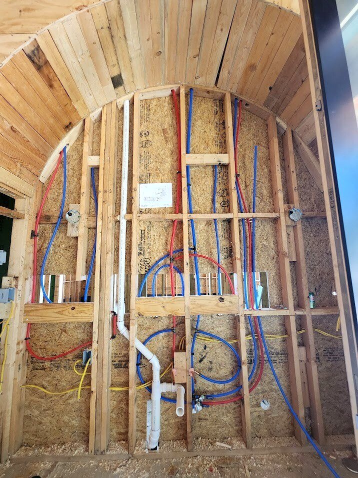 Top-out stage with PEX supply lines and drain plumbing in framed walls