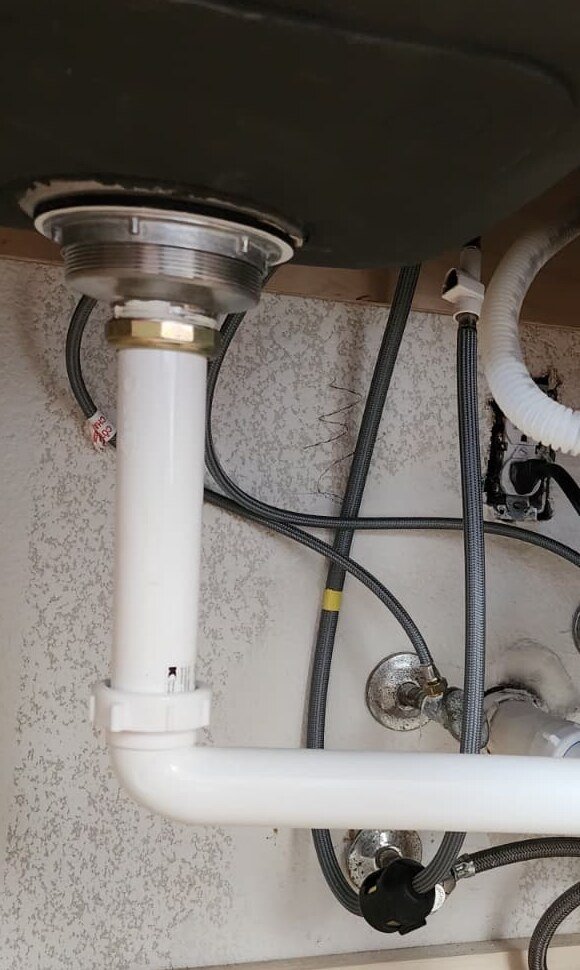 Sink drain and supply connections under a kitchen sink